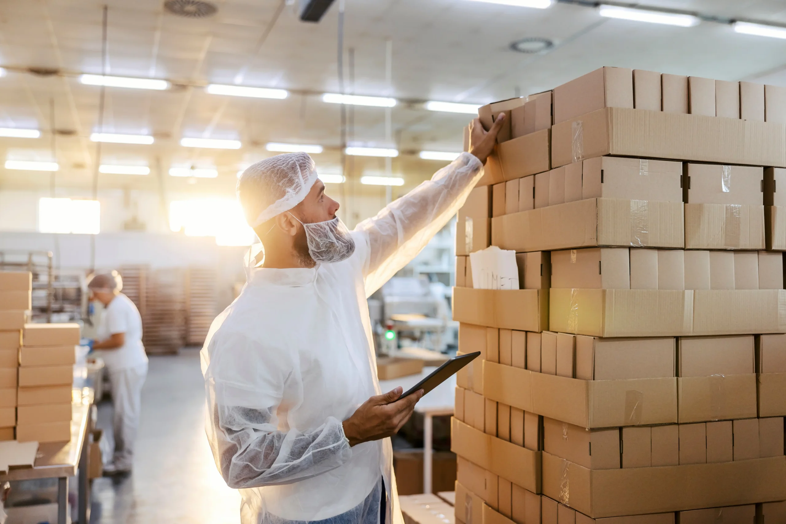 man wearing protective gear at food manufacturing plant surveying the product