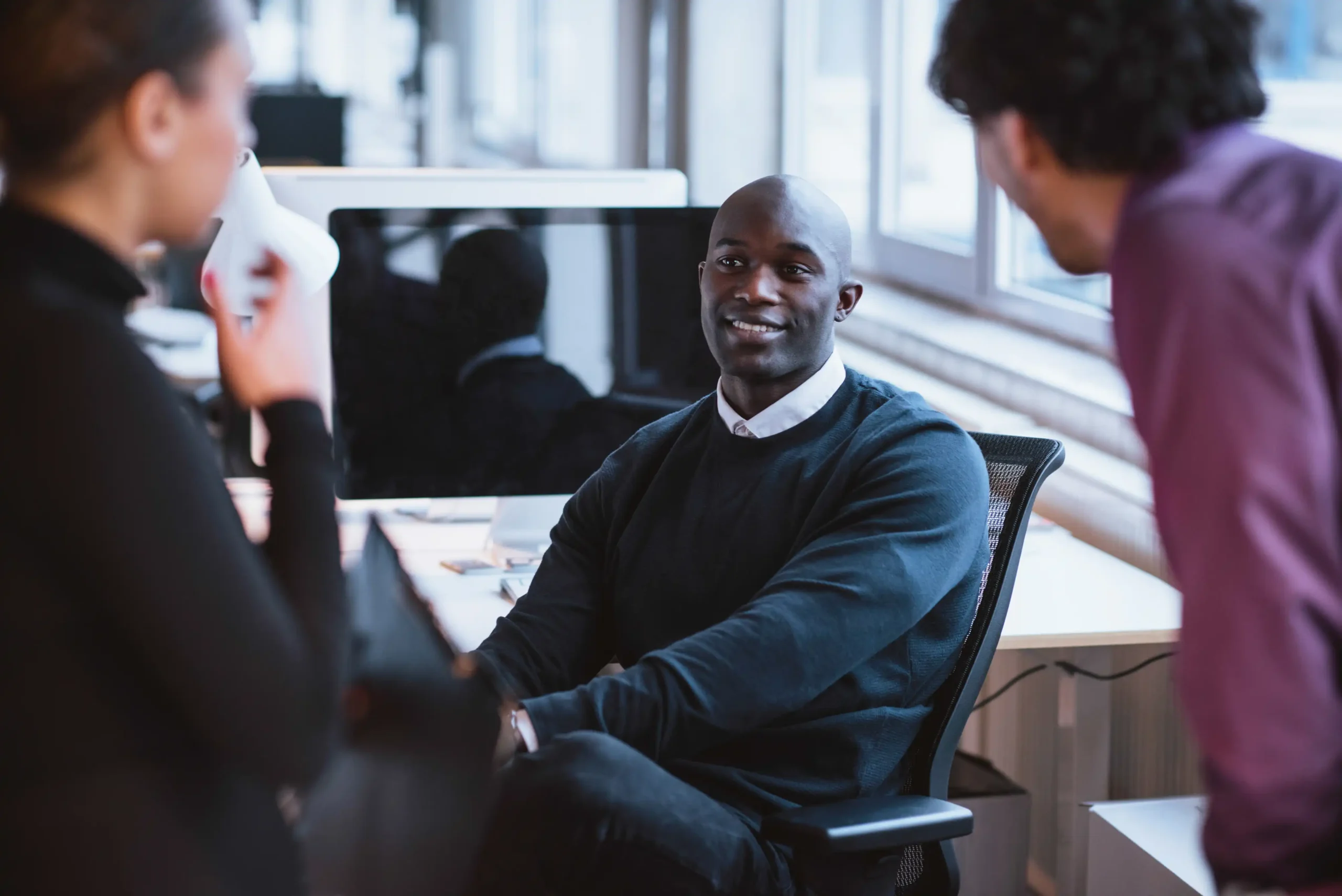 Professionals conversing at desk in office