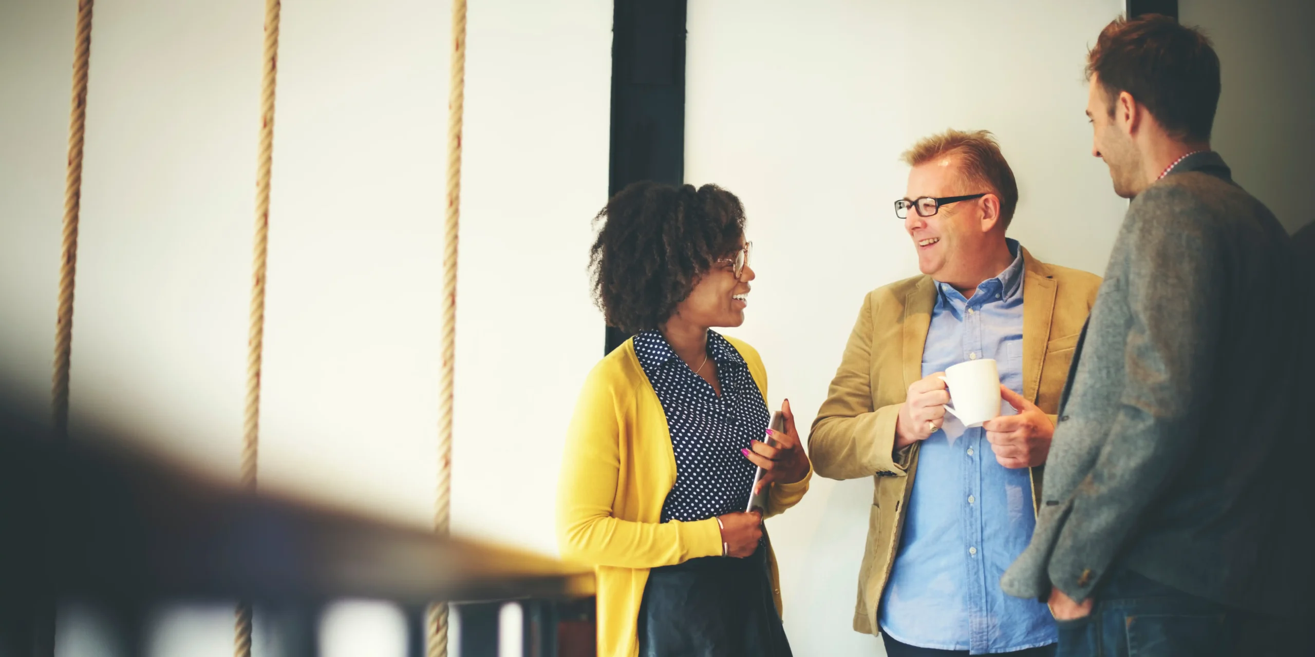 Three coworkers standing and chatting with coffee