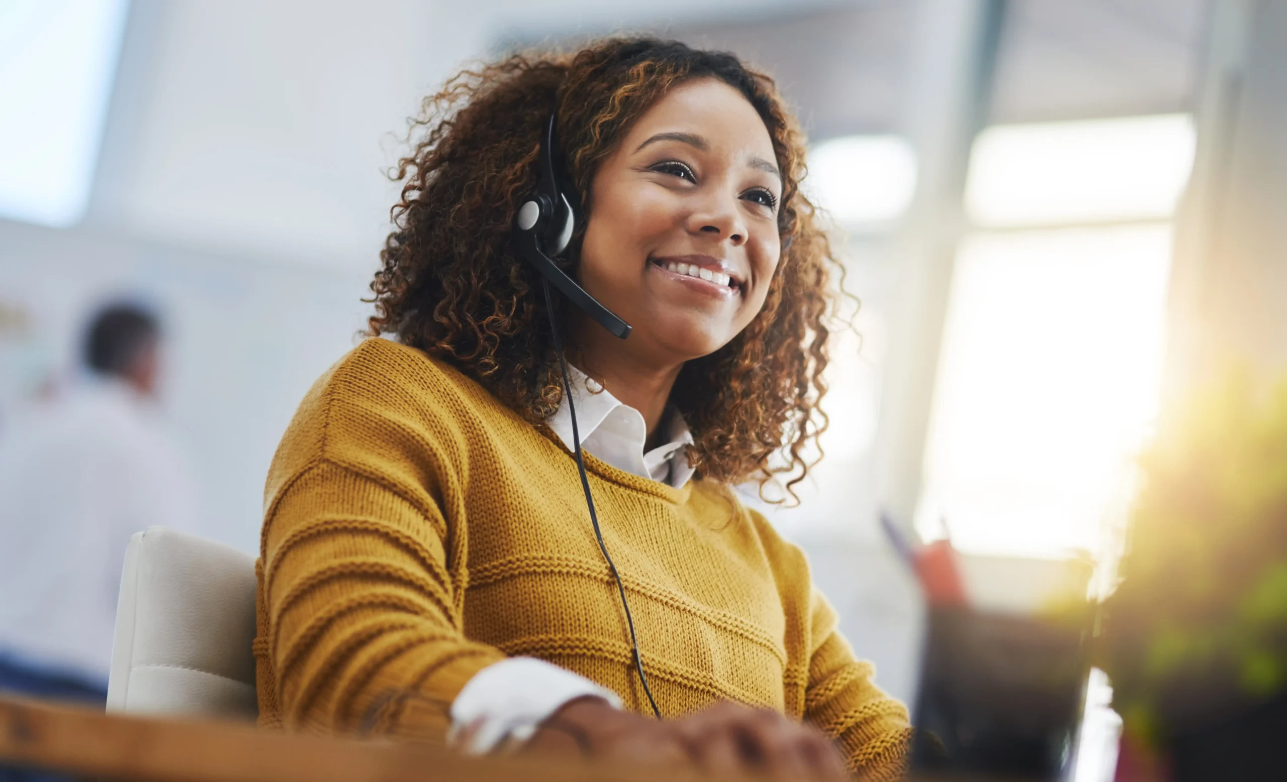 Customer service agent with headset smiling at desk