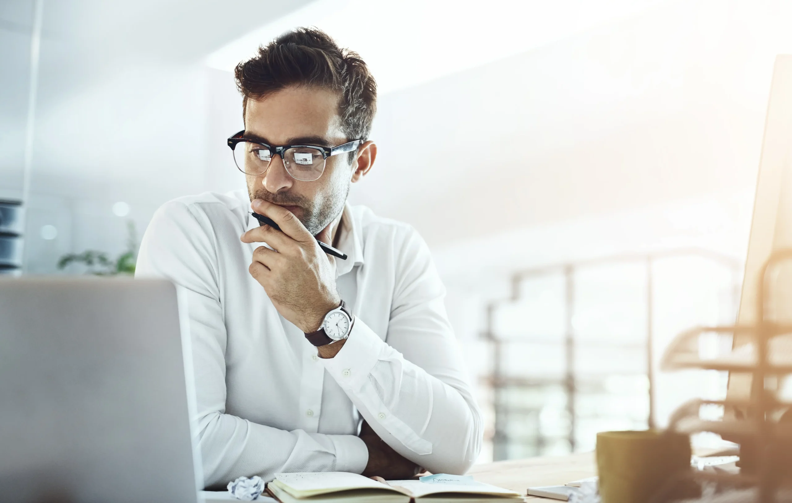 Man sitting at desk looking at computer monitor, making a decision