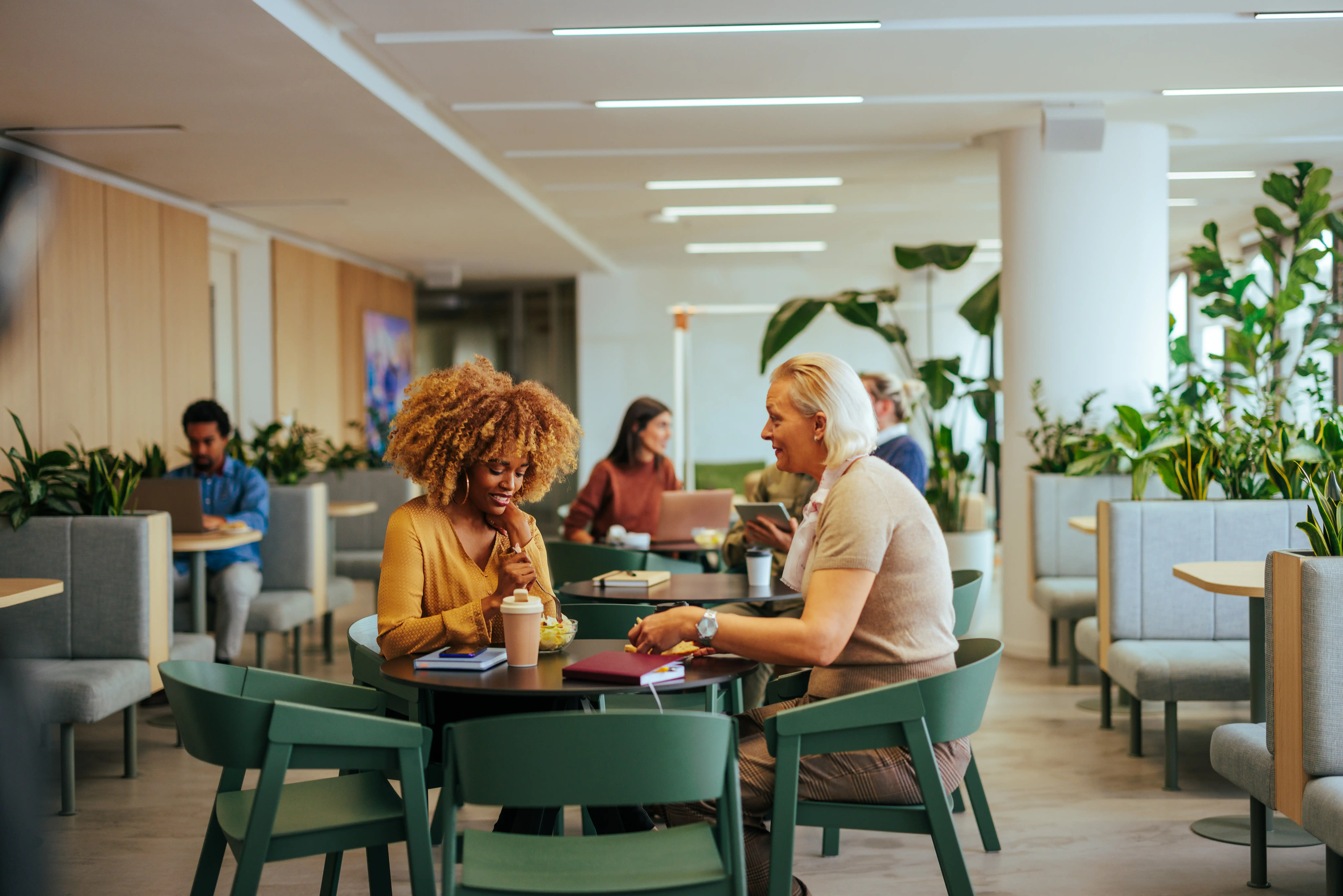 Two professional women at a table chatting over coffee