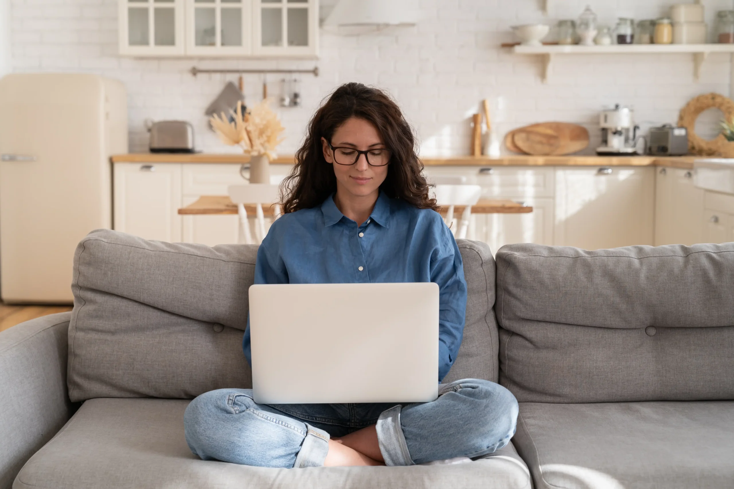 Professional woman working happily from home on couch with laptop
