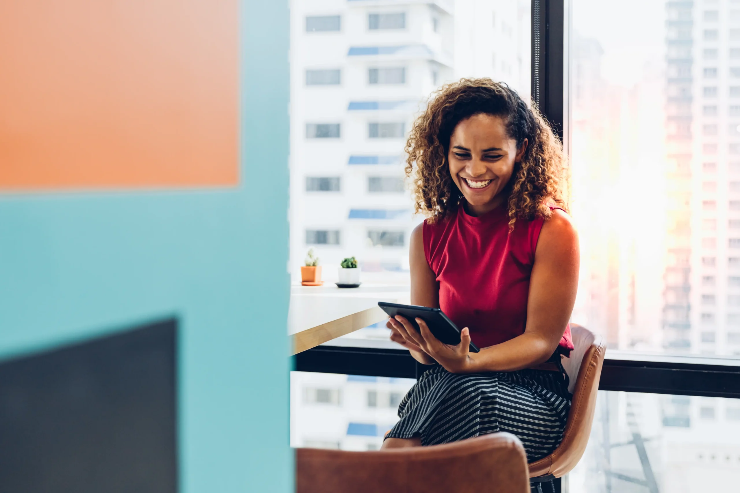 Happy woman in corner office looking at ipad