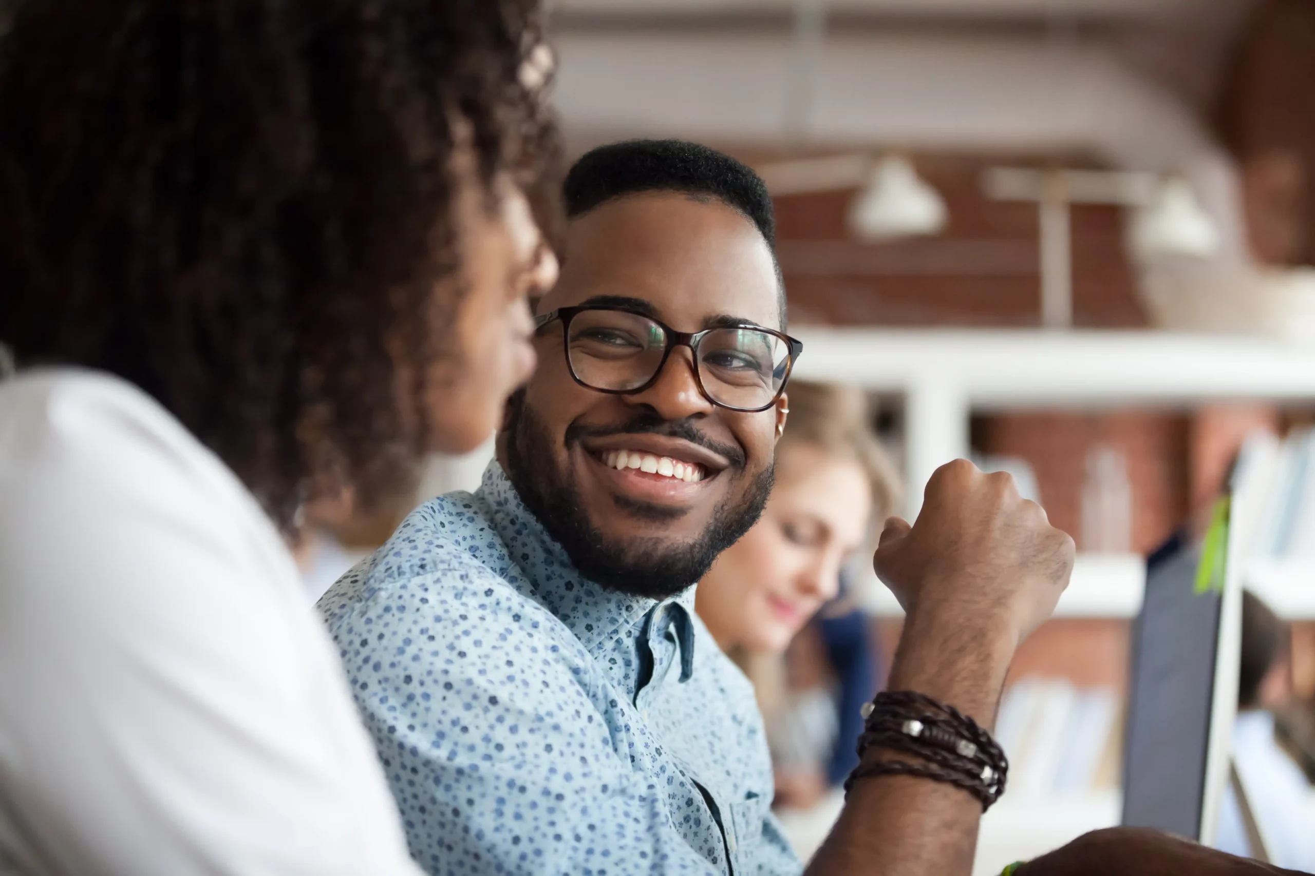 colleagues at shared desk smiling as they co-work