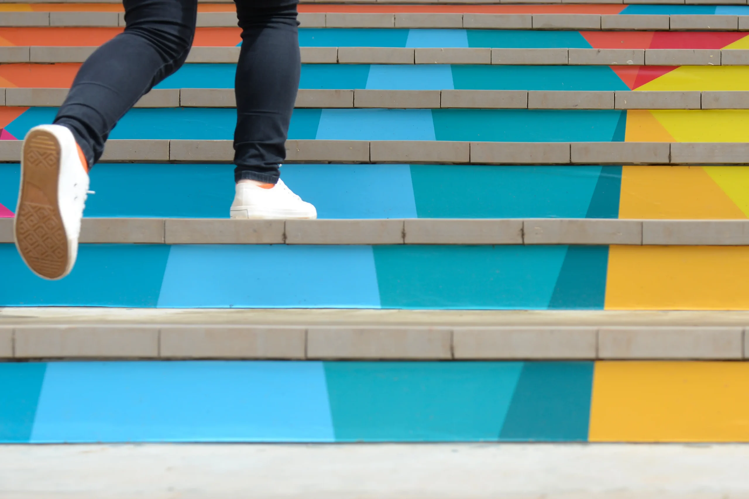 feet in white sneakers running up colorful staircase