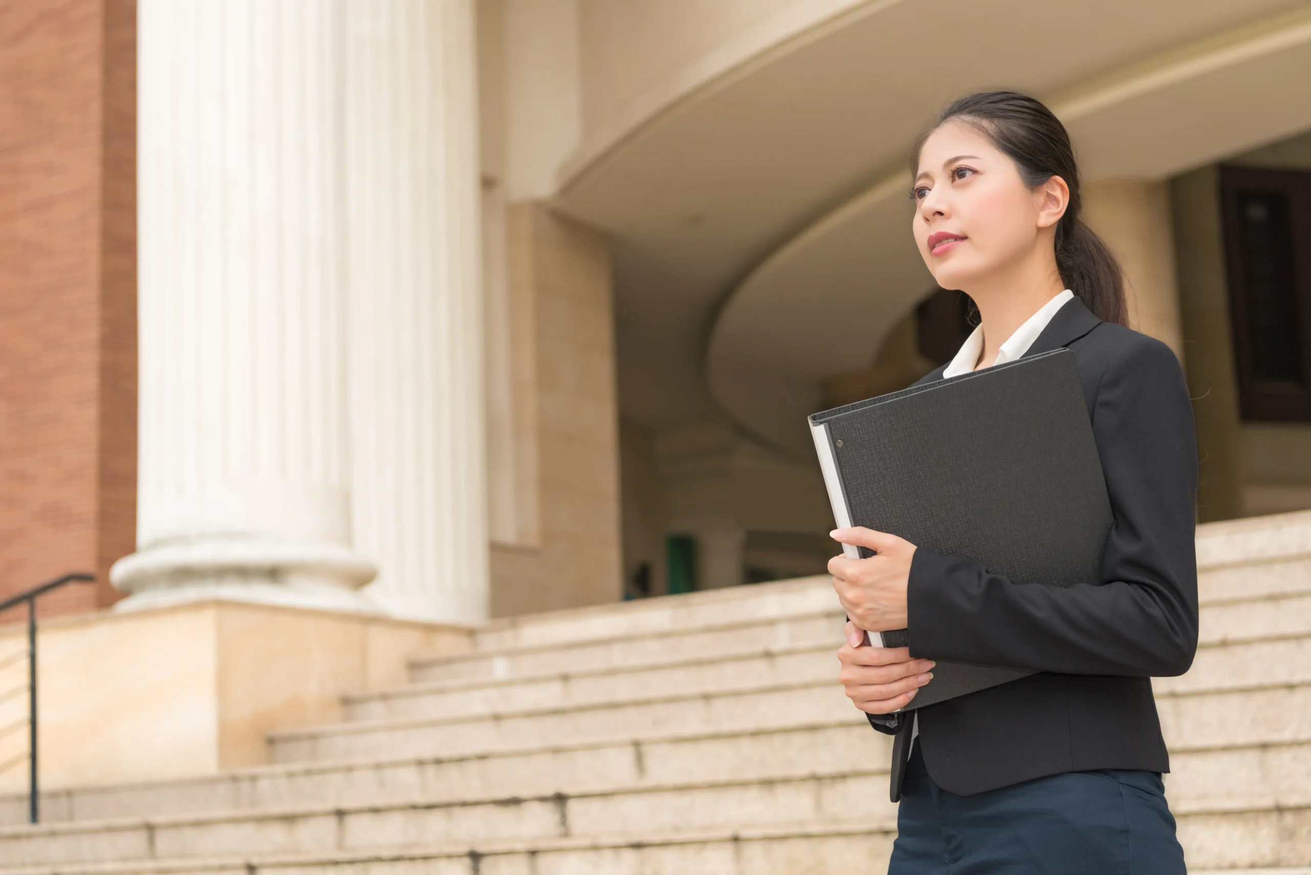Professional woman holding binder standing outside government building