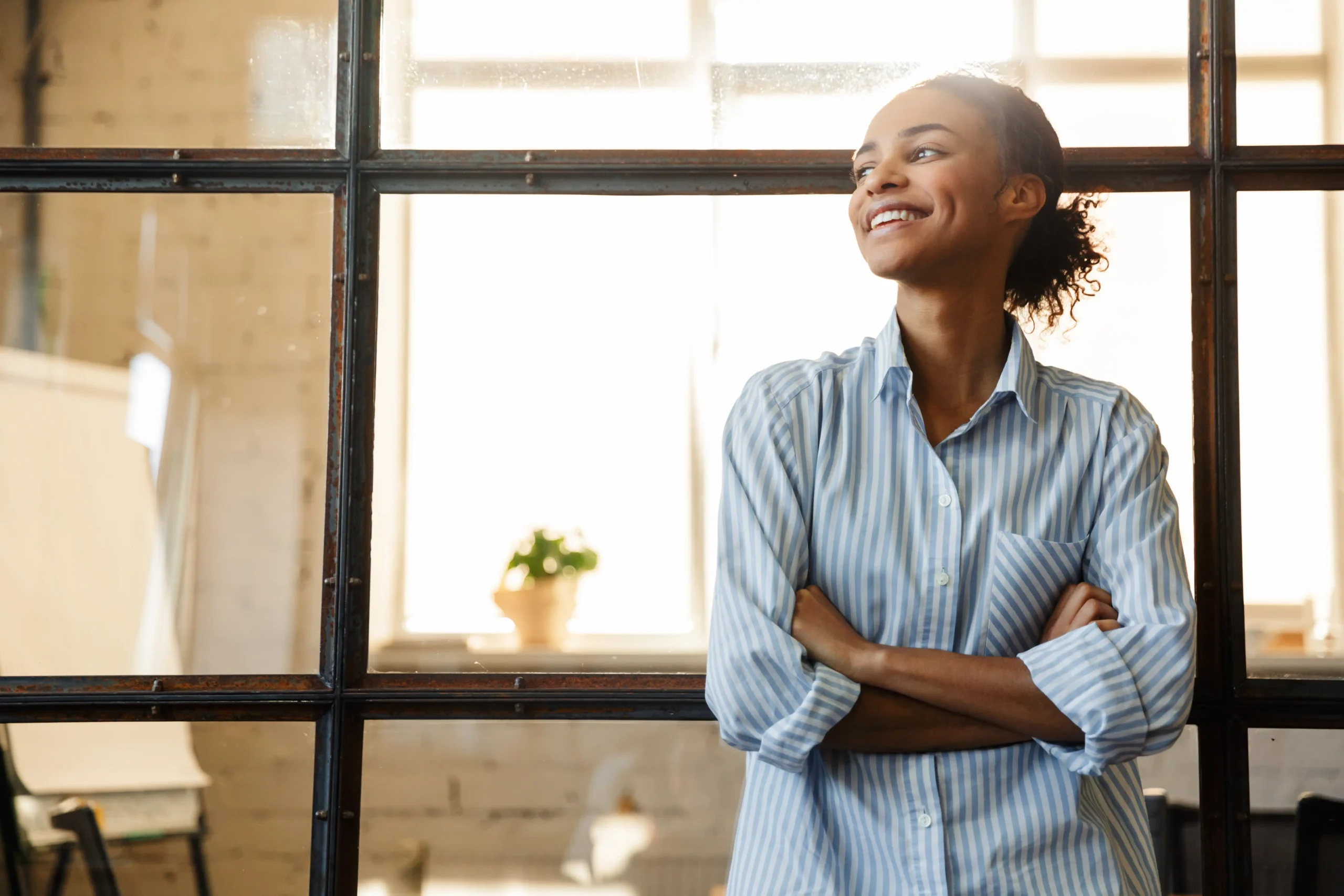 Young woman at modern office in striped shirt smiling looking off camera