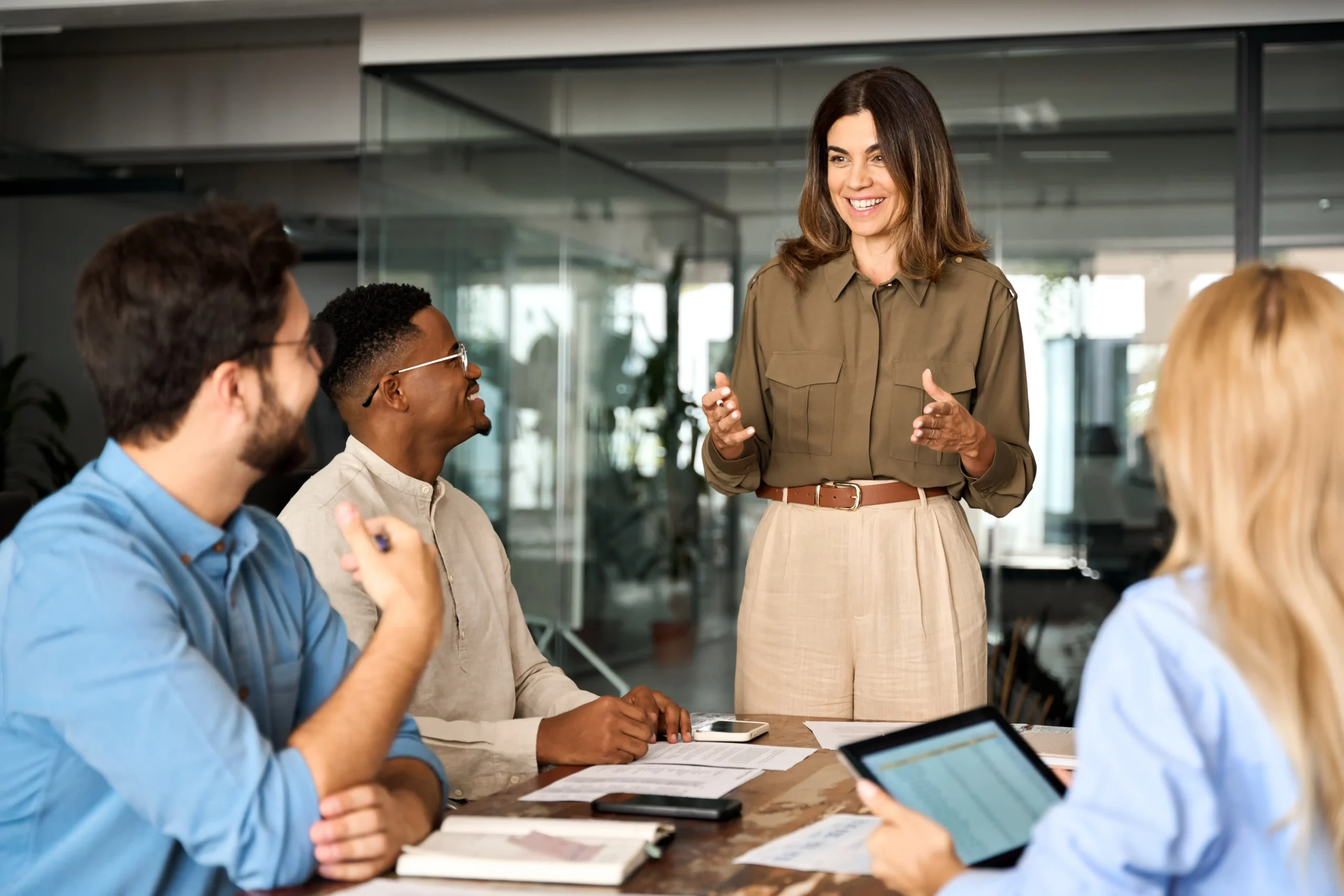 Team meeting with smiling boss standing at the head of the table