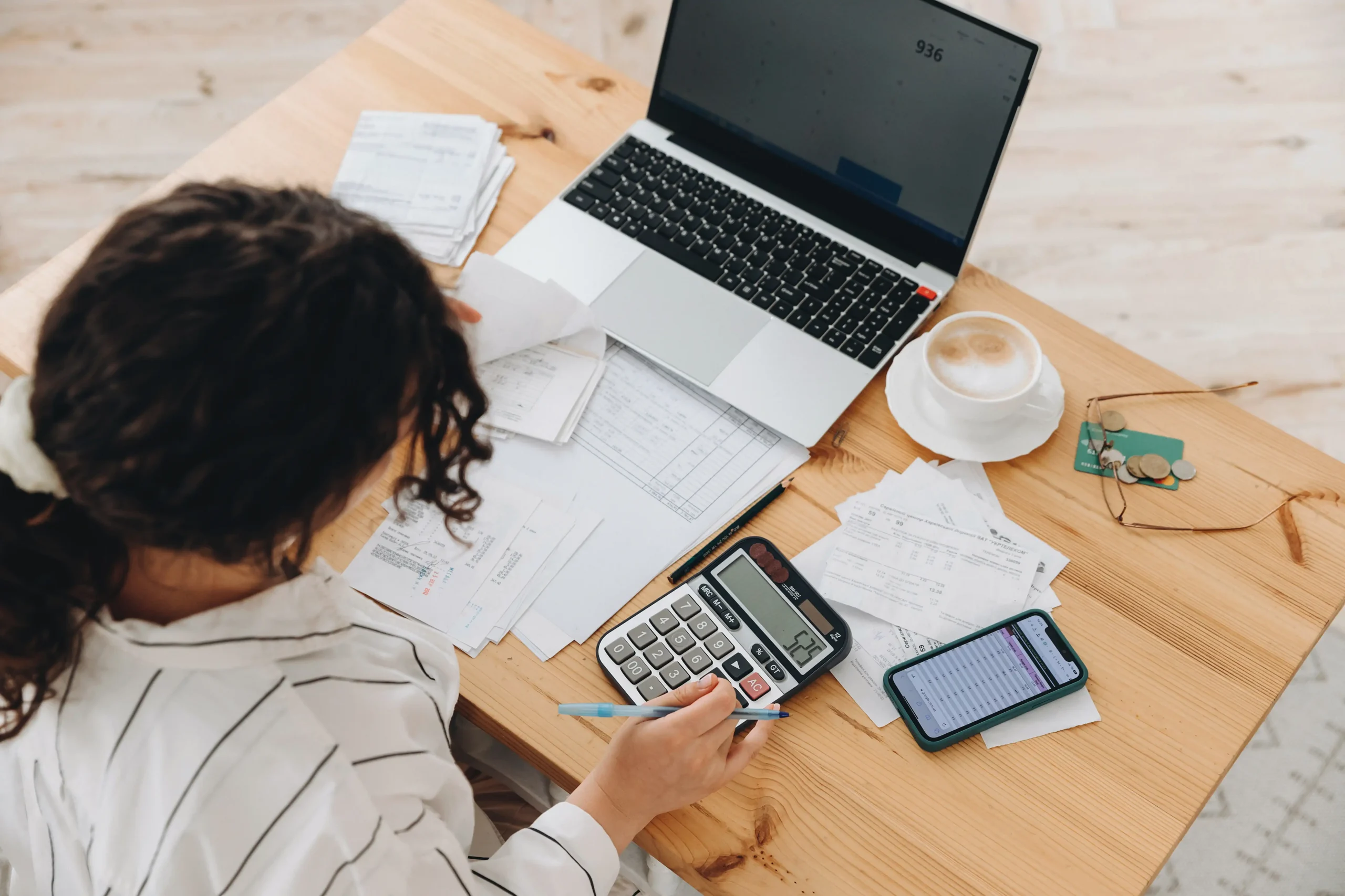 woman working on calculator at desk with screens