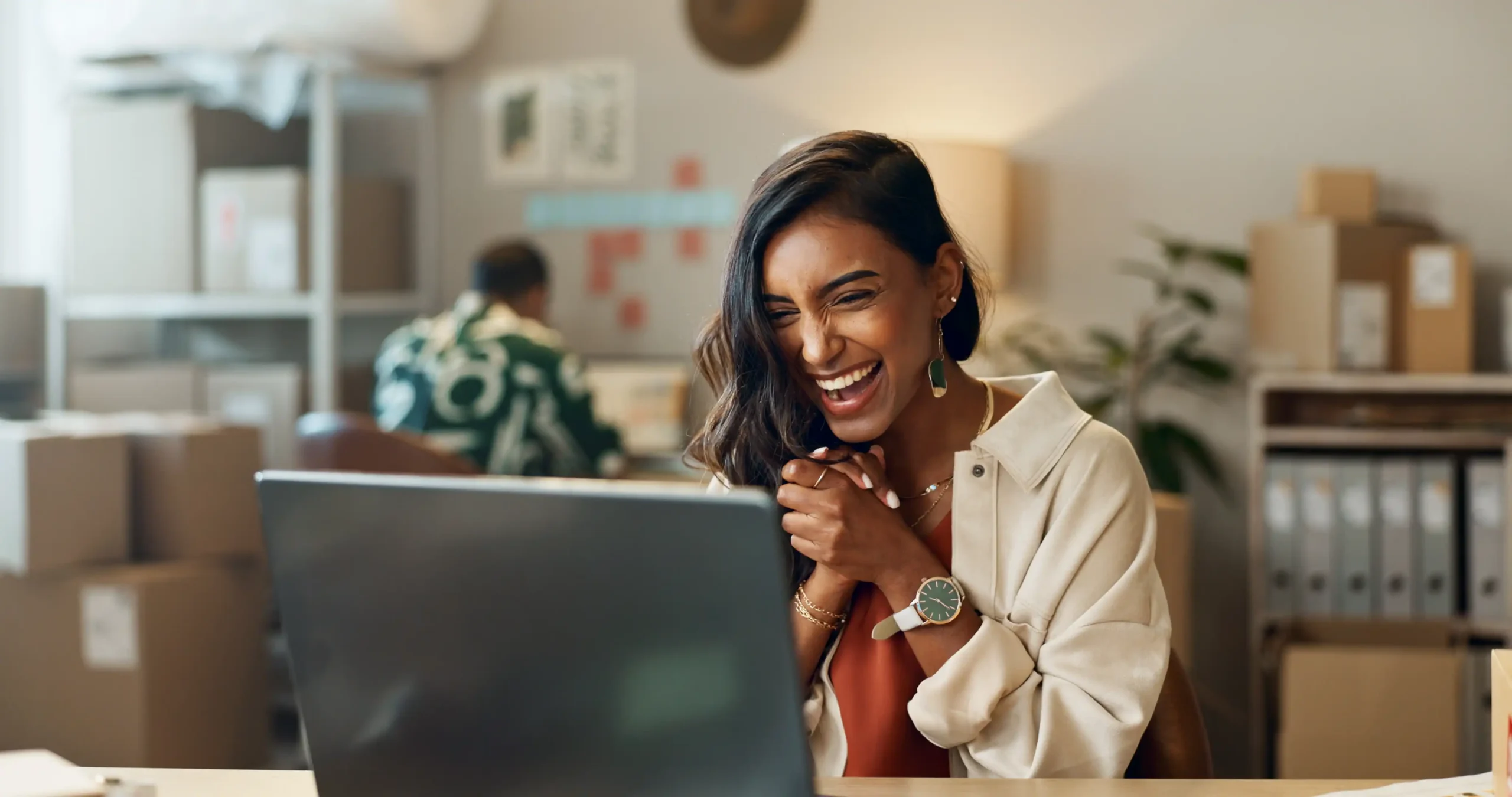 woman on laptop with boxes celebrating