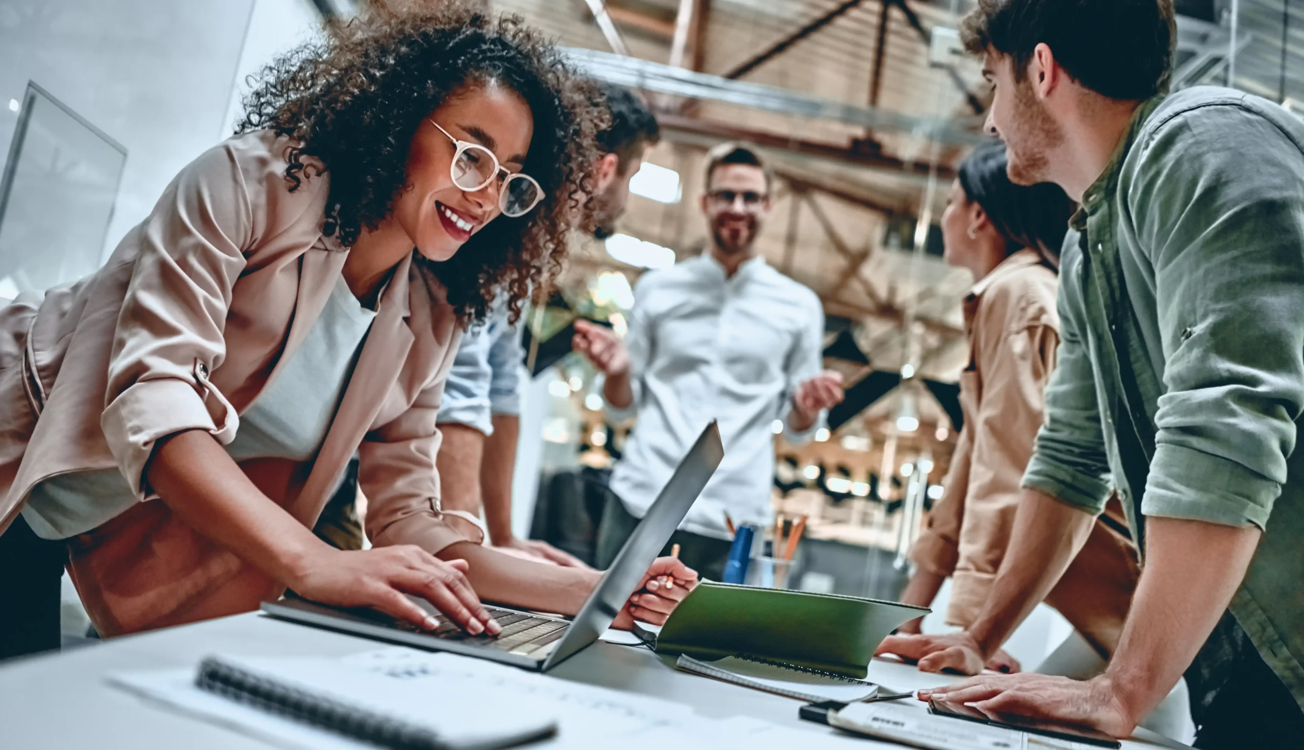 people standing around table at work with computer